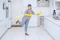 Cheerful housewife playing guitar with a broom