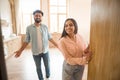 Cheerful indian couple inviting guests to enter home, happy people standing in doorway of modern flat Royalty Free Stock Photo