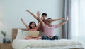 Cheerful indian family teenage boy son and girl with dad have fun and raising hands up together while relaxing and using laptop Royalty Free Stock Photo