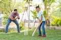 Cheerful indian father encouraging son from behind while playing cricket game at park - concept of Motivation, Guidance Royalty Free Stock Photo