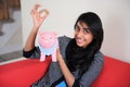 Cheerful Indian girl holding coin and piggybank