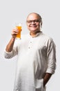 Cheerful Indian old man holding or drinking fresh orange or mango juice in glass Royalty Free Stock Photo