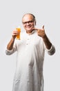 Cheerful Indian old man holding or drinking fresh orange or mango juice in glass Royalty Free Stock Photo