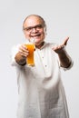 Cheerful Indian old man holding or drinking fresh orange or mango juice in glass Royalty Free Stock Photo