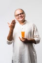 Cheerful Indian old man holding or drinking fresh orange or mango juice in glass Royalty Free Stock Photo