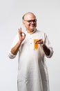 Cheerful Indian old man holding or drinking fresh orange or mango juice in glass Royalty Free Stock Photo