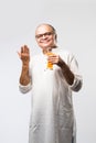 Cheerful Indian old man holding or drinking fresh orange or mango juice in glass Royalty Free Stock Photo