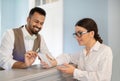 Receptionist Man Helping Businesswoman Book Hotel Room Via Smartphone Indoors Royalty Free Stock Photo