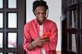 Cheerful inspired African American man smiling using smartphone for chatting with girlfriend Royalty Free Stock Photo
