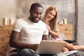 Cheerful international couple enjoying online shopping at home