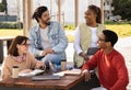 Cheerful international millennial students study and prepare project together at table with gadgets