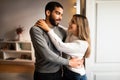 Cheerful international young family hugging, enjoy free time together, romantic date in minimalist room