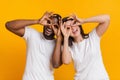 Cheerful interracial couple making funny glasses with fingers, fooling together