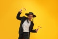 Cheerful Jewish man in hat, with sidelocks holding noisemaker, against yellow background. Celebration