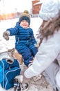 Cheerful and joyful boy of 4-6 years old, sitting on a bench, mother changes shoes to skates. Hand gesture of the child Royalty Free Stock Photo