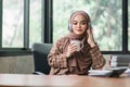 The cheerful and joyful millennial Asian Muslim woman is enjoying listening to music through her headphones while