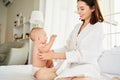 A cheerful joyful young mother in a bathrobe plays with her newborn baby son after a shower Royalty Free Stock Photo