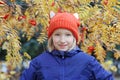 Cheerful kid girl smiling, the child is dressed in a funny knitted warm hat with ears, looks like a fox. Autumn, outdoors portrait Royalty Free Stock Photo