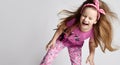 Cheerful kid girl in summer clothing colorful pants and t-shirt has fun jumping, dancing, shaking head, laughing loudly