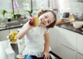 Cheerful kid holding an apple, kitchen shot