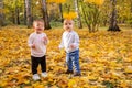 cheerful kids catching maple leaves falling in autumn city Park