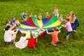 Cheerful kids playing with multicolor parachute and small balls
