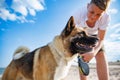 Teenage guy with blond hair and leash in hands plays and walks with dog of Akina Inu breed on wild beach along Black Sea Royalty Free Stock Photo