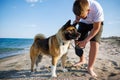 Teenage guy with blond hair and leash in hands plays and walks with dog of Akina Inu breed on wild beach along Black Sea Royalty Free Stock Photo