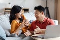 Cheerful korean couple planning vacation, using laptop