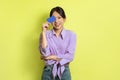 Cheerful Korean Female Holding Credit Card Near Face, Yellow Background