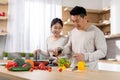 Cheerful korean husband and wife making vegetable salad