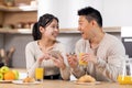 Cheerful korean spouses having breakfast, checking smartphone