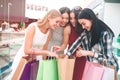 Cheerful ladies are looking down into one bag and putting their hands into it. They are amazed and excited.