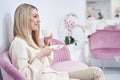 Cheerful lady drinking beverage in wellness center foyer