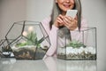 Joyful woman using cellphone in room with florariums Royalty Free Stock Photo