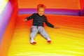 A cheerful, laughing boy sitting and slide down on a bright yellow rubber trampoline. Image in motion, a brave child is not afraid Royalty Free Stock Photo