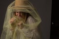 Cheerful laughing girl with brown hat wrapped in tulle on a dark background Royalty Free Stock Photo