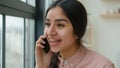 Cheerful laughing Indian Arabian girl gen z student speak mobile phone at office casual carefree conversation happy Royalty Free Stock Photo