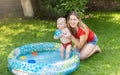 Portrait of cheerful laughing mother with baby boy playing in inflatable swimming pool Royalty Free Stock Photo