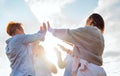 cheerful laughing women rising hands Up making High Five during outdoor walking with bright evening sun backlight. Woman's