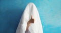 Cheerful lazy woman waking up after sleeping covered head with white blanket showing cool gesture her fingers on blue background