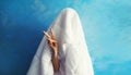 Cheerful lazy woman waking up after sleeping covered head with white blanket showing cool gesture her fingers on blue background