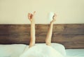 Cheerful lazy woman waking up after sleeping lying in soft comfortable bed showing empty cup coffee stretching her hands up from