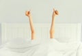Cheerful lazy woman waking up after sleeping lying in soft comfortable bed showing gesture stretching her hands up from under the