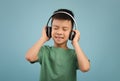 Cheerful little asian boy listening to music in wireless headphones Royalty Free Stock Photo