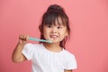 Cheerful little asian girl brushes teeth, has brilliant smile, morning daily hygiene, poses with toothbrush, isolated