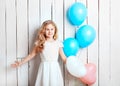 Cheerful little blonde girl with balloons on white wood backgrou Royalty Free Stock Photo