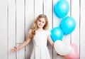 Cheerful little blonde girl with balloons on white wood backgrou Royalty Free Stock Photo
