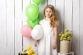 Cheerful little blonde girl with balloons on white wood background Royalty Free Stock Photo