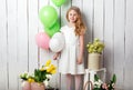 Cheerful little blonde girl with balloons on white wood background Royalty Free Stock Photo
